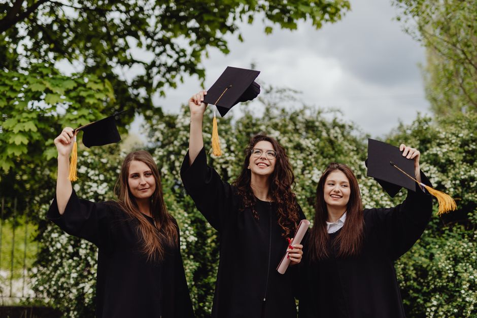 Three young women celebrating their graduation in caps and gowns.